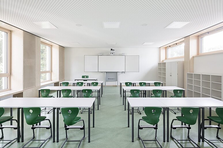 Klassenraum mit Whiteboard und grünen Stühlen