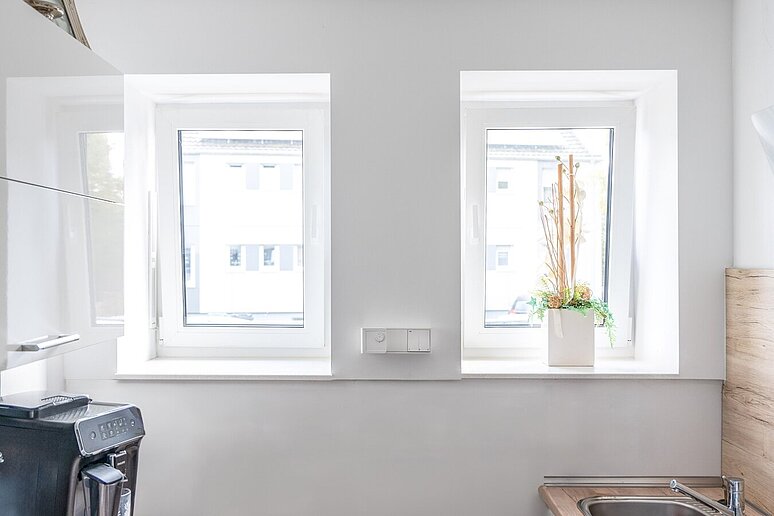 Blick aus einer Wohnung auf zwei Fenster und Fensterbänke