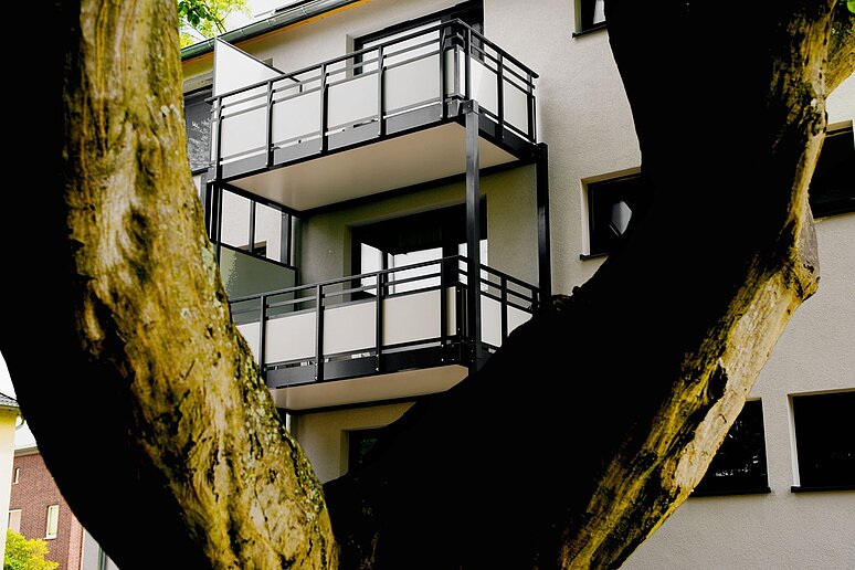 Haus mit Balkonen hinter Baum