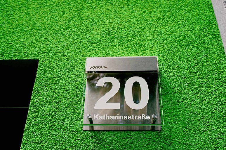 Hausnummer an Fassade auf grünem Hintergrund