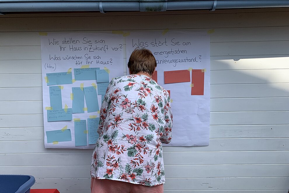 Frau steht mit dem Rücken vor Plakaten und Klebezetteln.