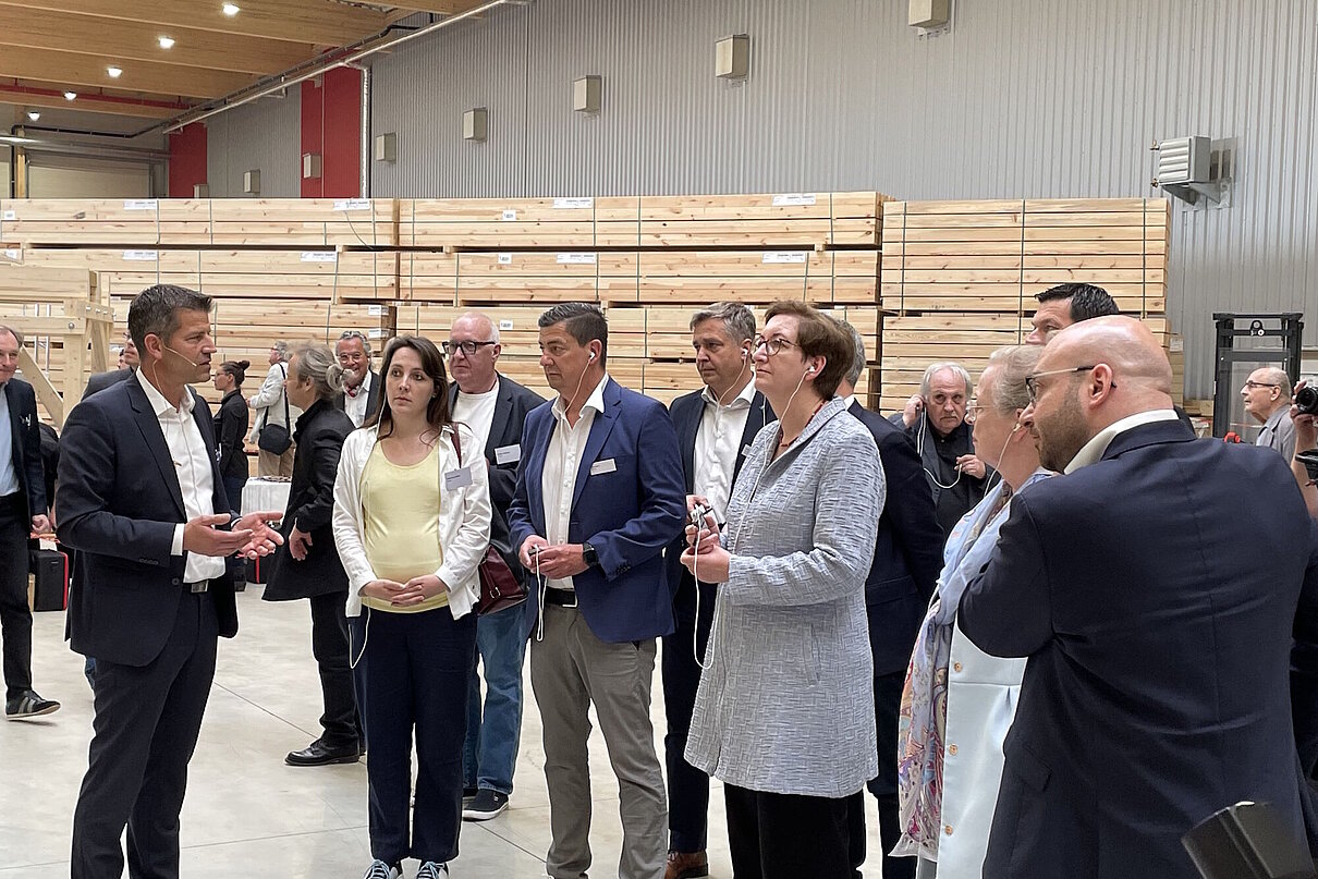 Personengruppe in Business-Kleidung in einem Werk, im Hintergrund Holzbalken