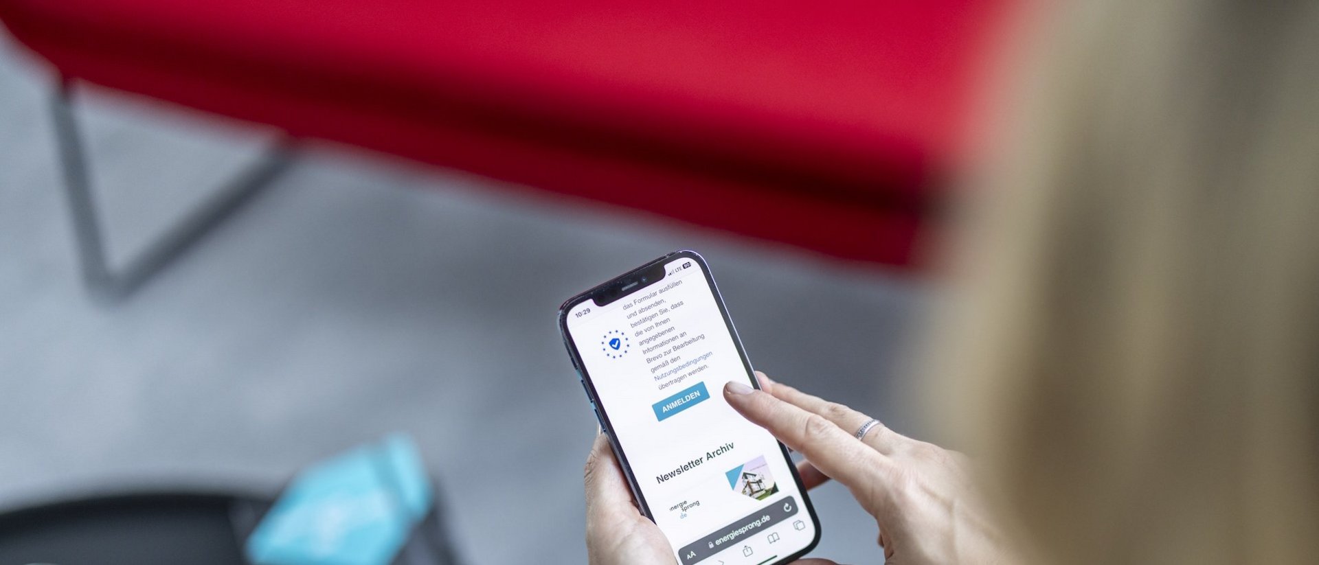 Zwei Hände halten ein Smartphone. Auf dem Display ist das Newsletter-Archiv der Website enegiesprong.de zu sehen.