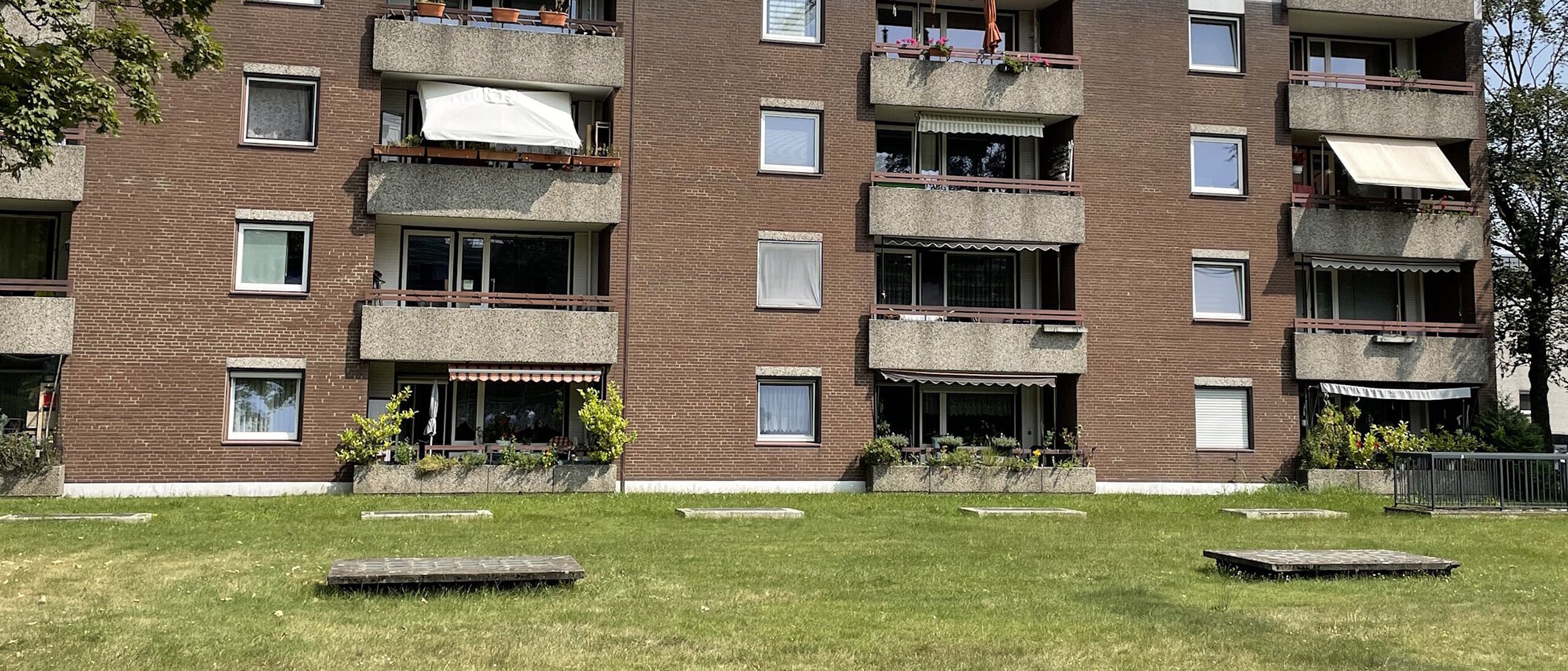 Mehrfamilienhaus viergeschossig mit Flachdach, Fenster und Balkone, davor Rasenfläche