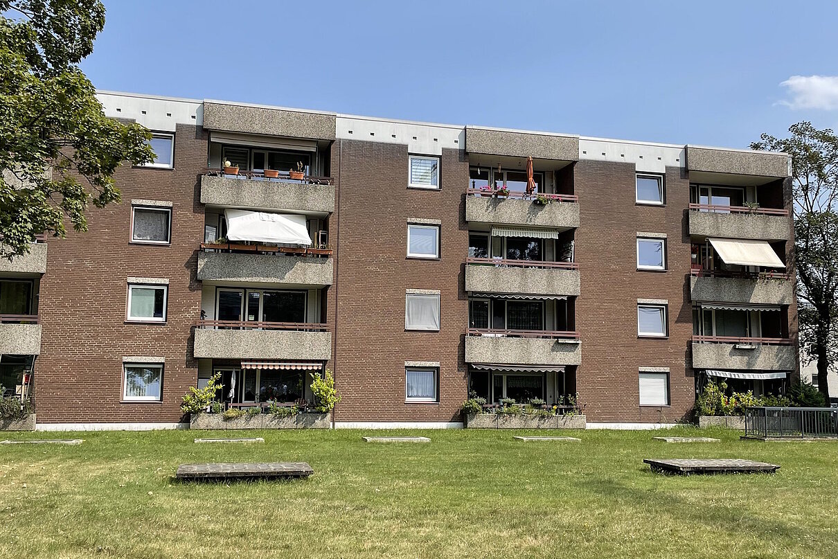 Mehrfamilienhaus viergeschossig mit Flachdach, Fenster und Balkone, davor Rasenfläche