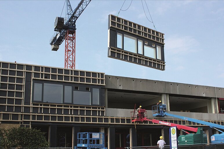 Baustelle mit Kran und vorgefertigten Fassadenteilen