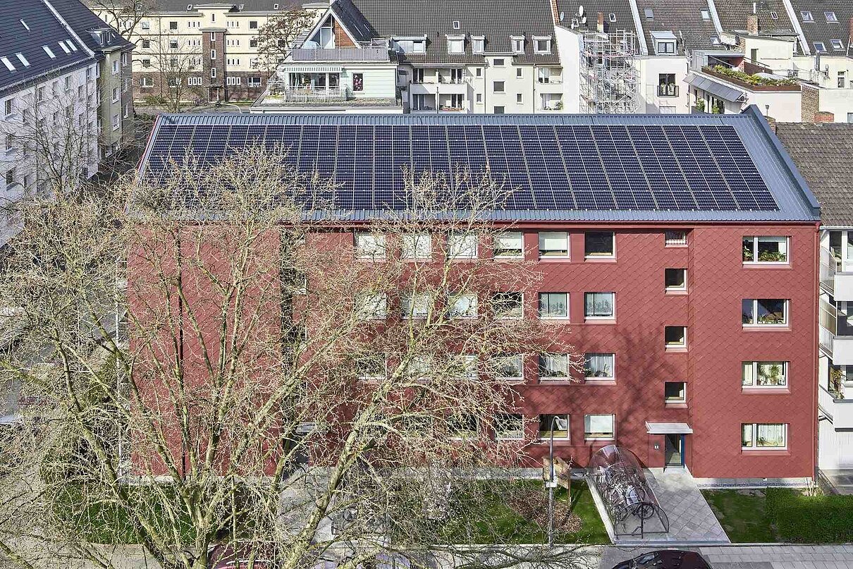 Luftansicht von Haus mit Photovoltaik hinter Baum