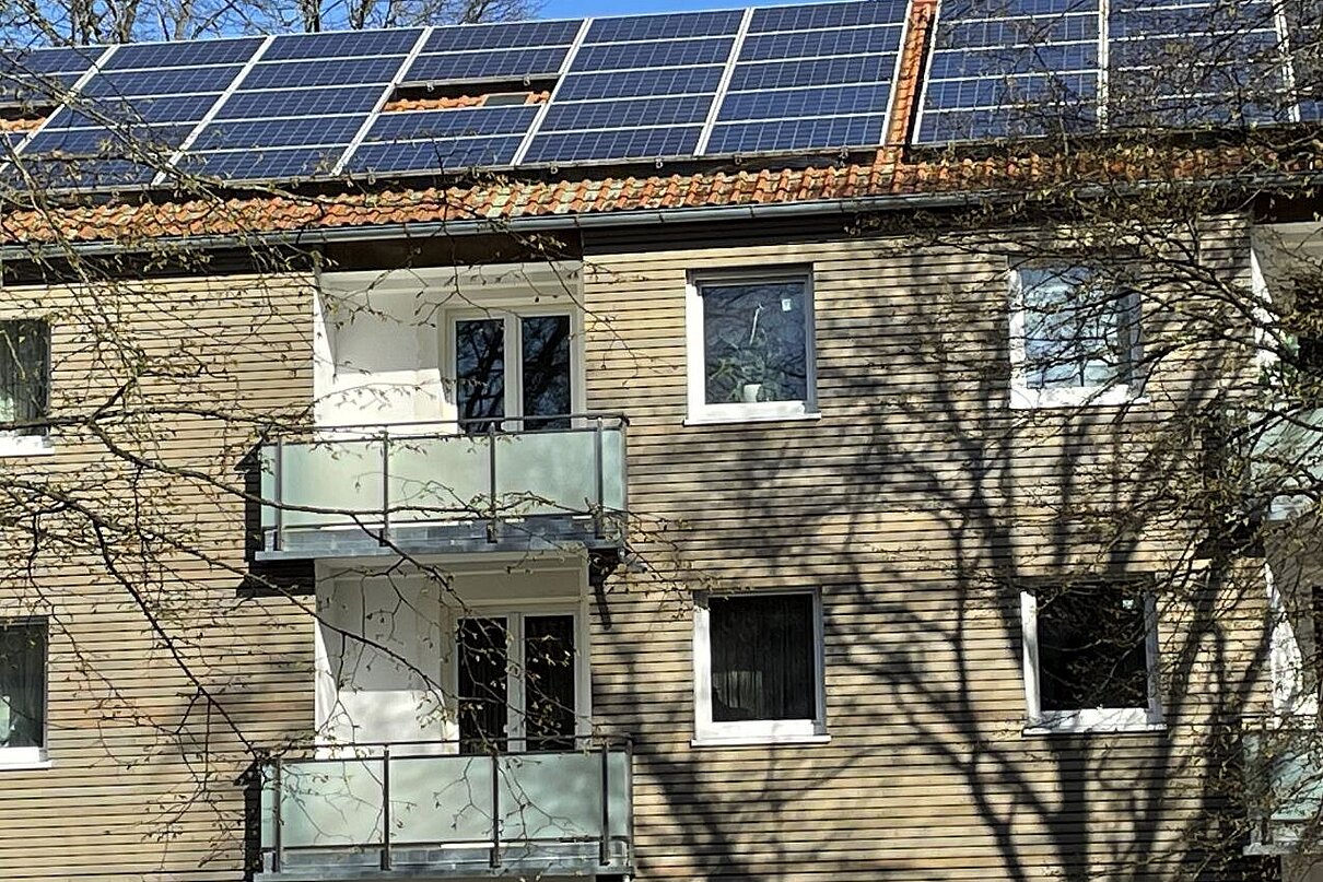 Mehrfamilienhaus mit Holzfassade und PV-Anlage auf dem Dach