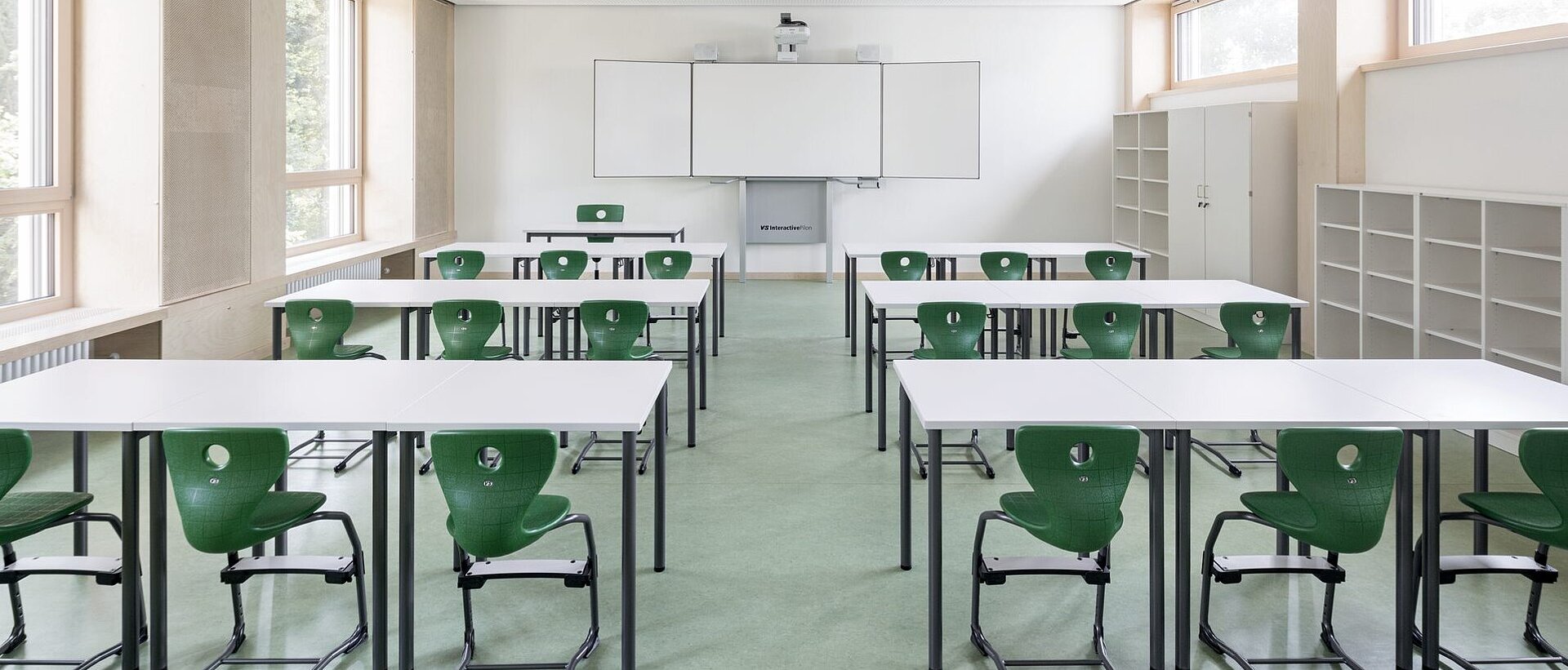 Klassenraum mit Whiteboard und grünen Stühlen