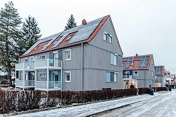 Mehrfamilienhaus nach Sanierung im Winter, davor eine Straße