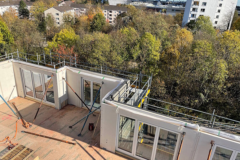 Aufstockung eines Hauses, im Hintergrund Laubbäume