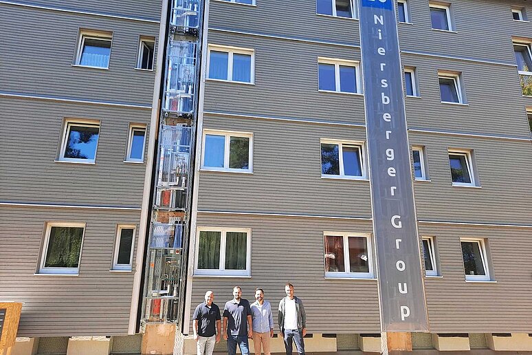 Vier Personen vor Mehrfamilienhaus mit neuer Fassade
