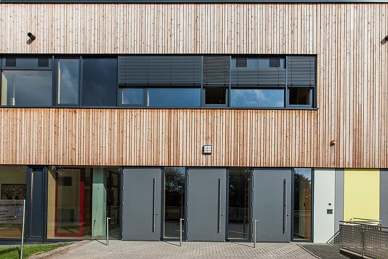 Holzfassade einer Schule mit Fenstern