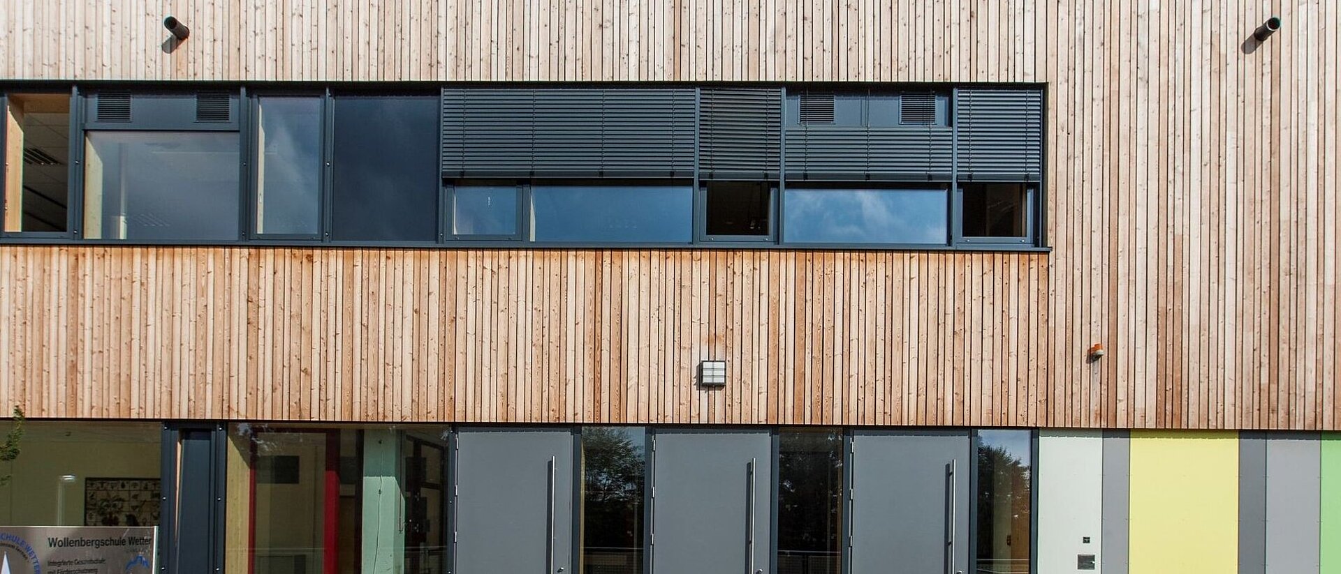 Holzfassade einer Schule mit Fenstern