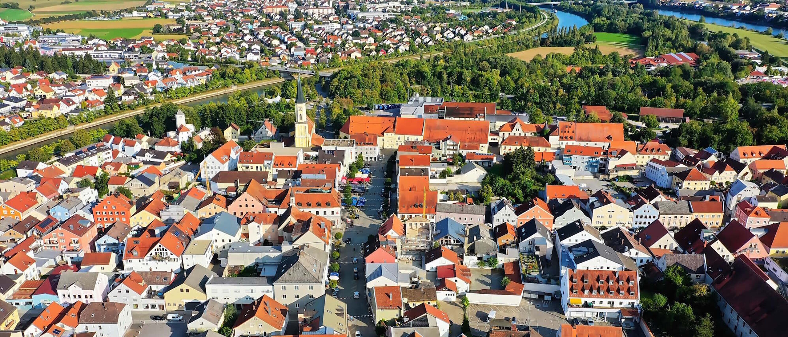 Kommune von oben, viele Häuser mit roten Ziegeldächern und Bäume