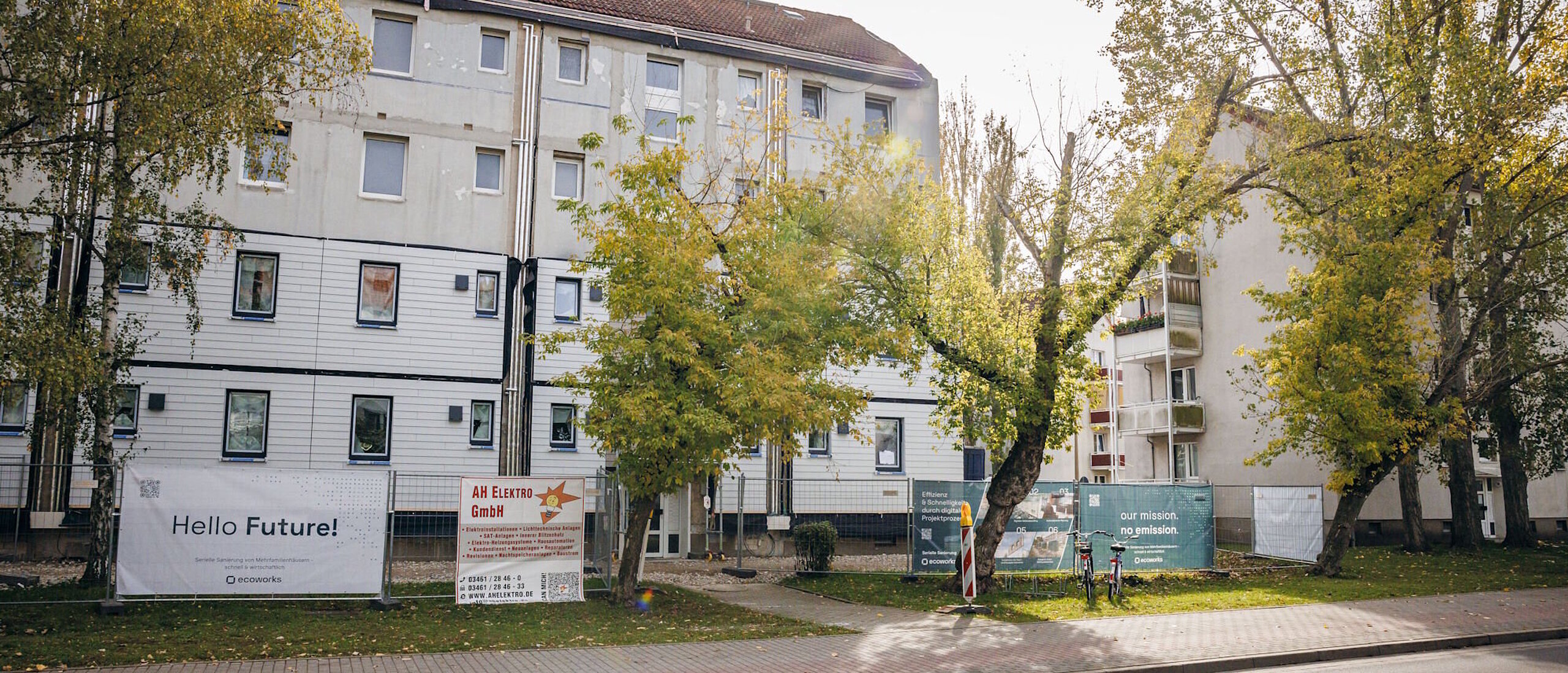 Mehrfasmilienhäuser, Laubbäume, Strasse und Fussweg