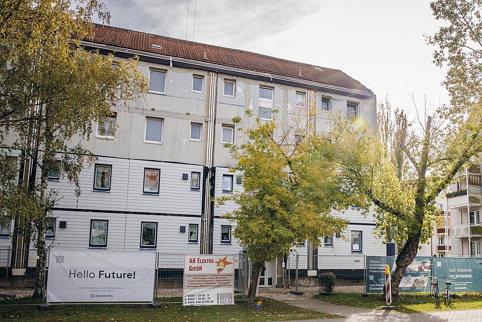 Mehrfasmilienhäuser, Laubbäume, Strasse und Fussweg