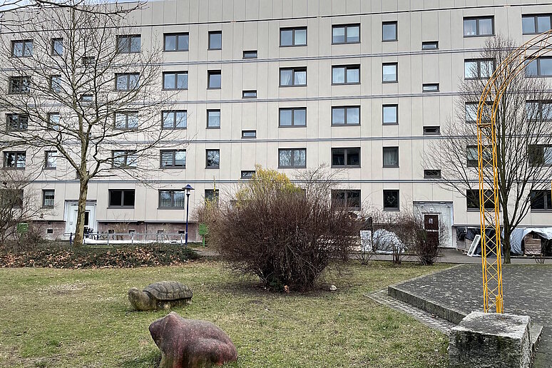 Plattenbau saniert, im Vordergrund Grünflächen mit Spielgeräten